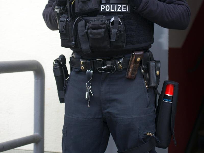 Ein Polizist steht vor einem Haus, in dem eine Razzia gegen durchgeführt wird.