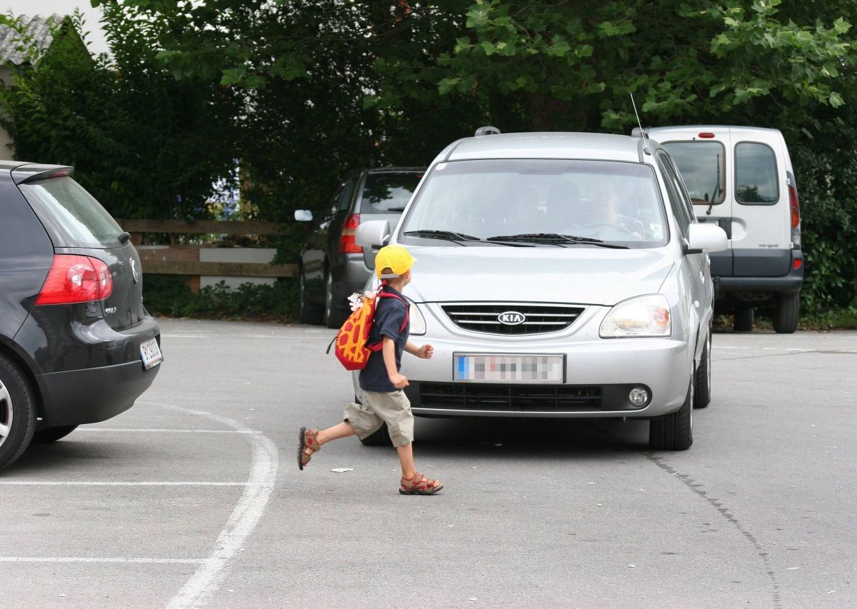 Kleiner Junge rennt über die Straße vor ein Auto