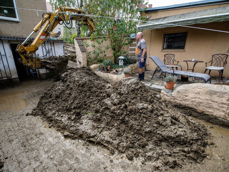 Eine Schlammlawine hat sich durch Tiefurt, einen Ortsteil von Weimar, gewälzt. Das Erdreich hatte sich am Freitagabend (17.08.2018) gelöst, als ein schweres Unwetter über die Region zog. Ein kurzer, aber heftiger Starkregen spülte das Material von einem Feld durch mehrere Grundstücke. Am Tag danach machten sich die Anwohner an die Aufräumarbeiten. Das Unwetter hatte auch an anderen Stellen in Weimar für Schäden gesorgt. So stürzte in der Innenstadt in einer Wohnung durch Wassereinbruch eine Zimmerdecke ein; von Bäumen brachen viele Äste ab, in einen davon fuhr ein Linienbus. Der Park an der Ilm sowie die Parks in Tiefurt und Belvedere wurden gesperrt.