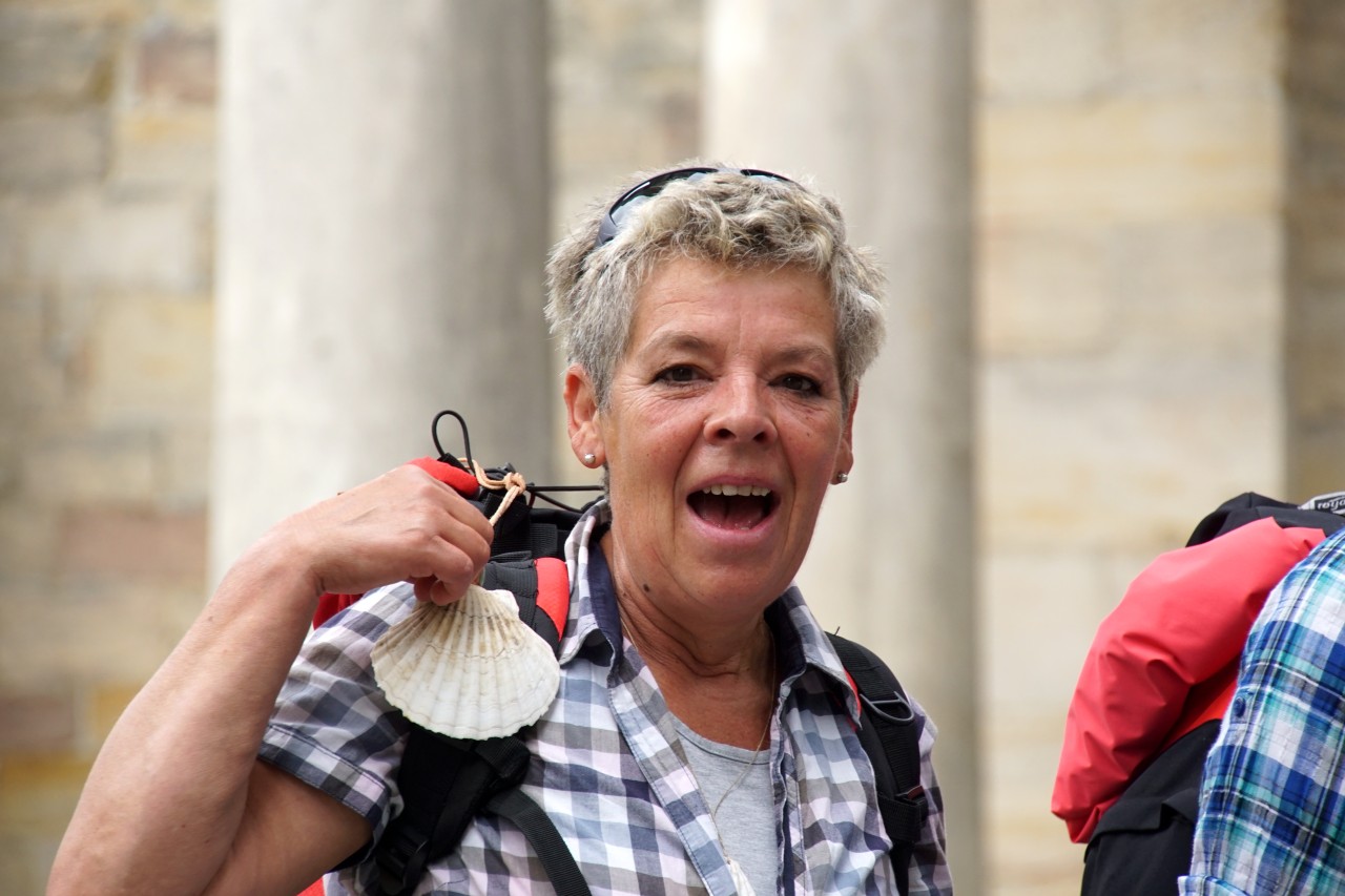 Margit zeigt die Muschel, dass Symbol des Jakobsweges. 