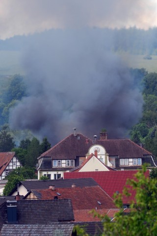 Eine Rauchsäule steigt am 16.06.2017 über dem Ort Effelder (Thüringen) im Landkreis Sonneberg auf. Dort war ein privates Anwesen mit mehreren Scheunen in Flammen aufgegangen. Die Anwohner hätten das Haus rechtzeitig verlassen können, ein Feuerwehrmann hätte beim Löschen jedoch eine Rauchvergiftung erlitten, teilte die Polizei am Freitag mit. Die Gebäude brannten bis auf die Grundmauern nieder. Im Einsatz waren Feuerwehren aus Thüringen und dem benachbarten Bayern. Foto: Stefan Thomas/dpa