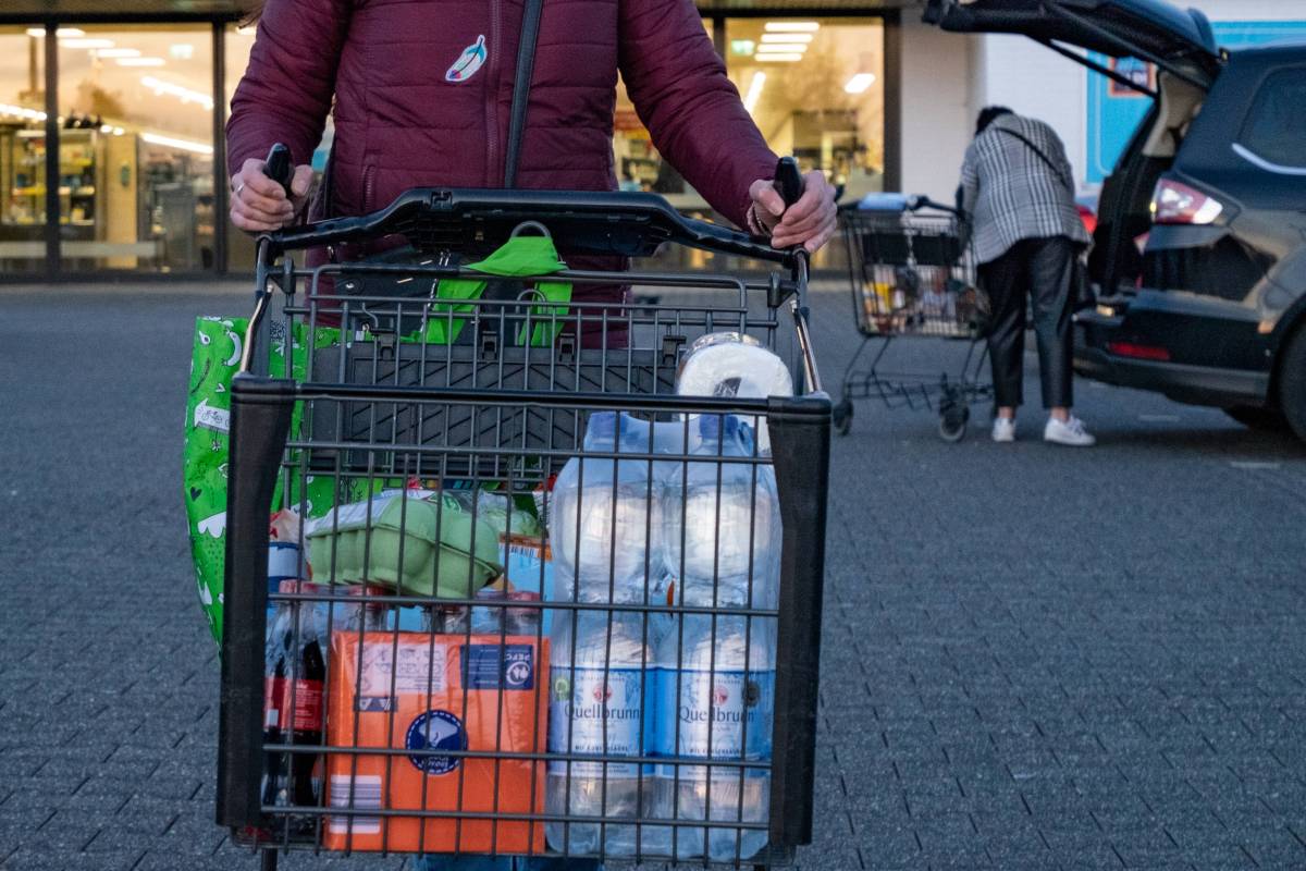 Frau schiebt auf einem Parkplatz einen Einkaufswagen