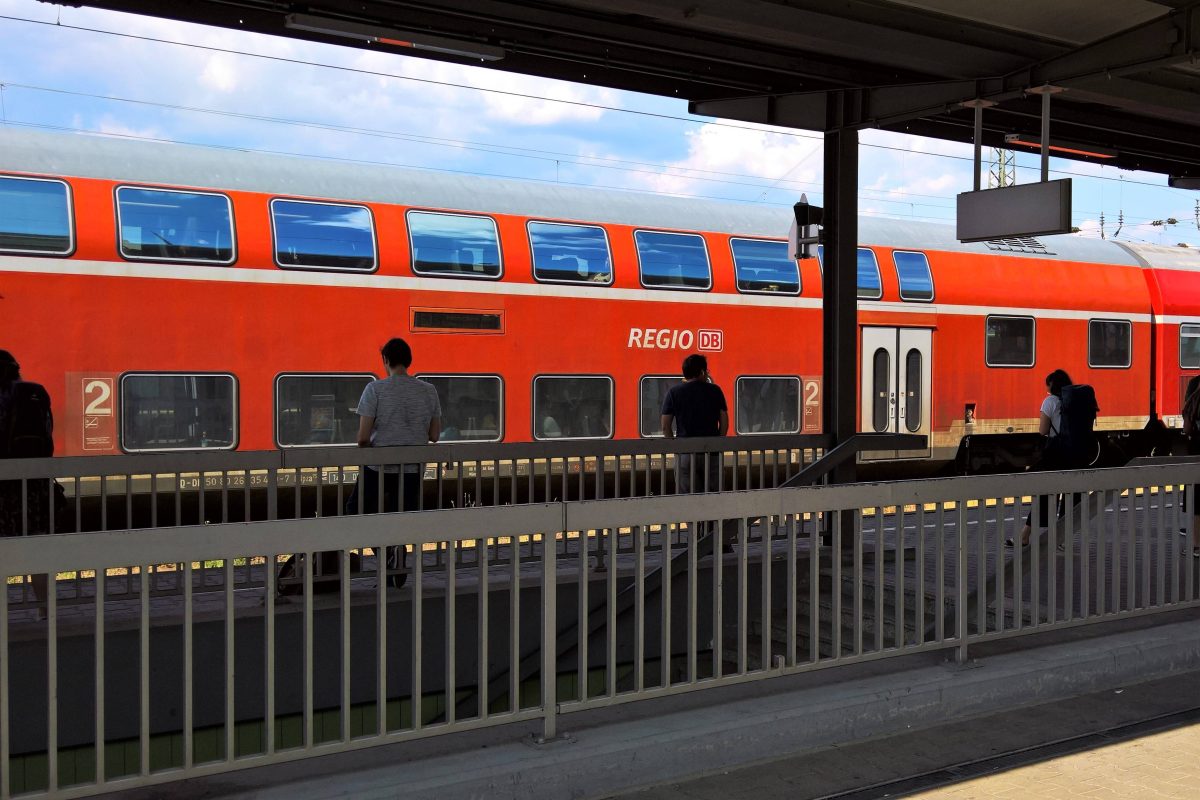 Fahrgäste stehen am Bahnsteig vor einem Regionalzug