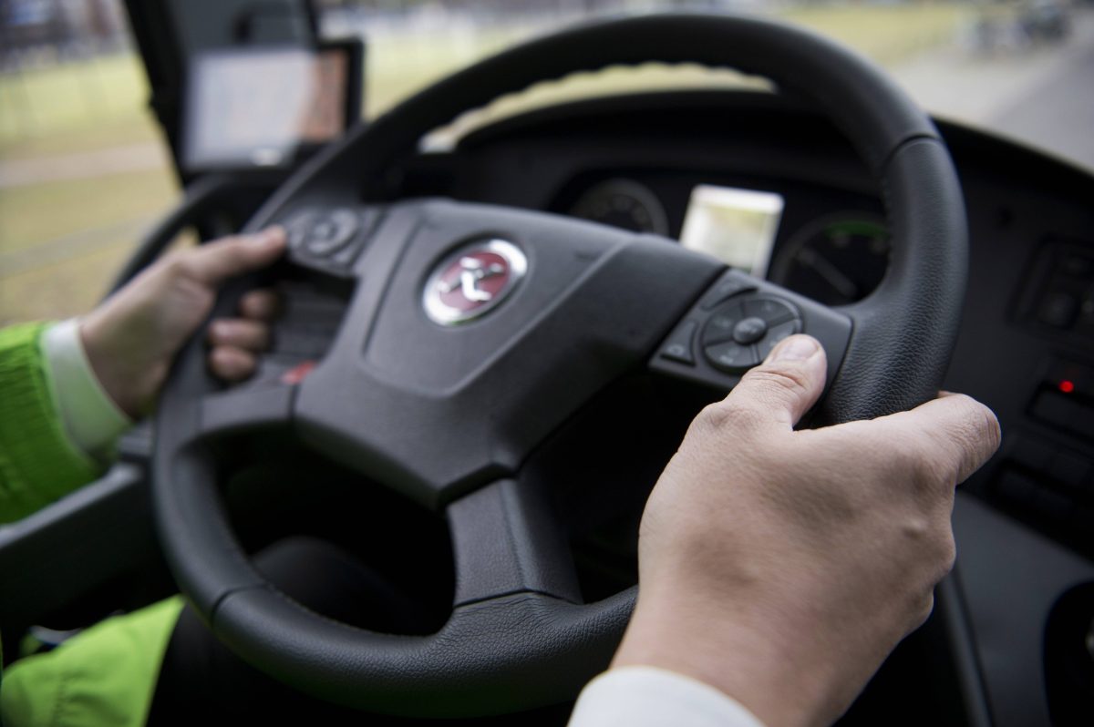 Mann hält Lenkrad im Bus in den Händen