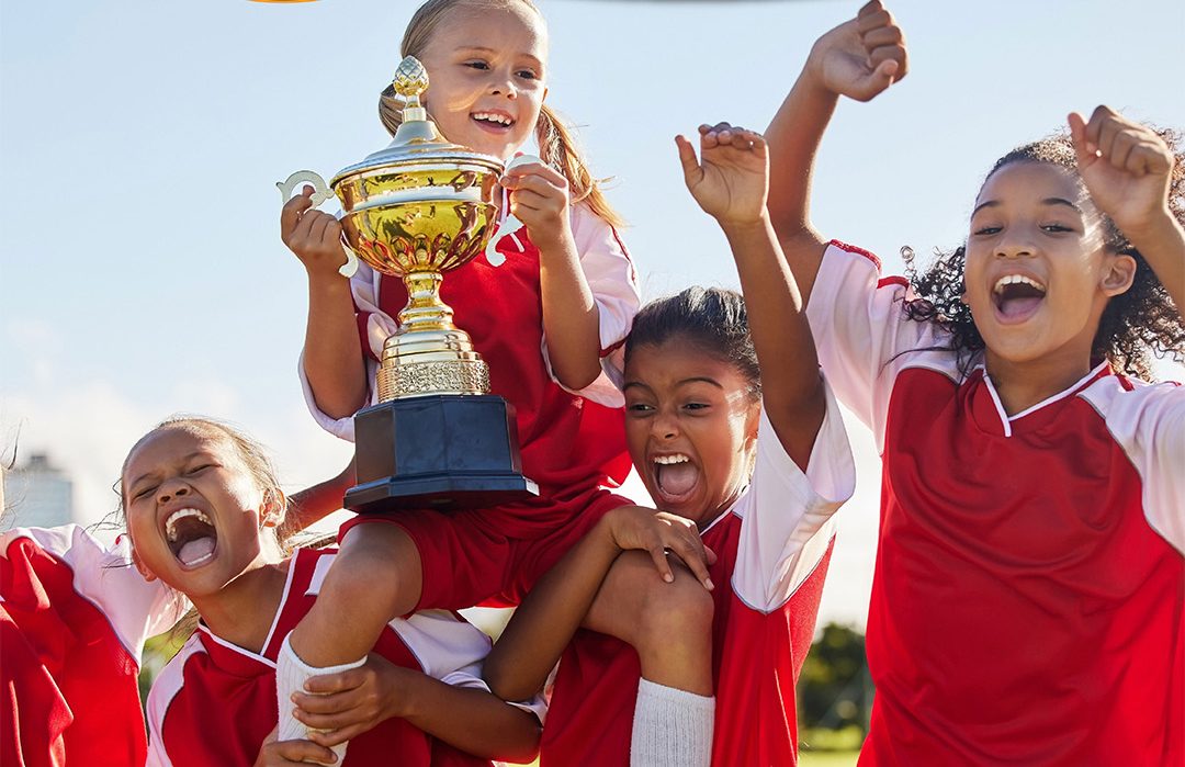 Junge Fußballerinnen freuen sich und halten einen Pokal in die Höhe (Symbolbild)